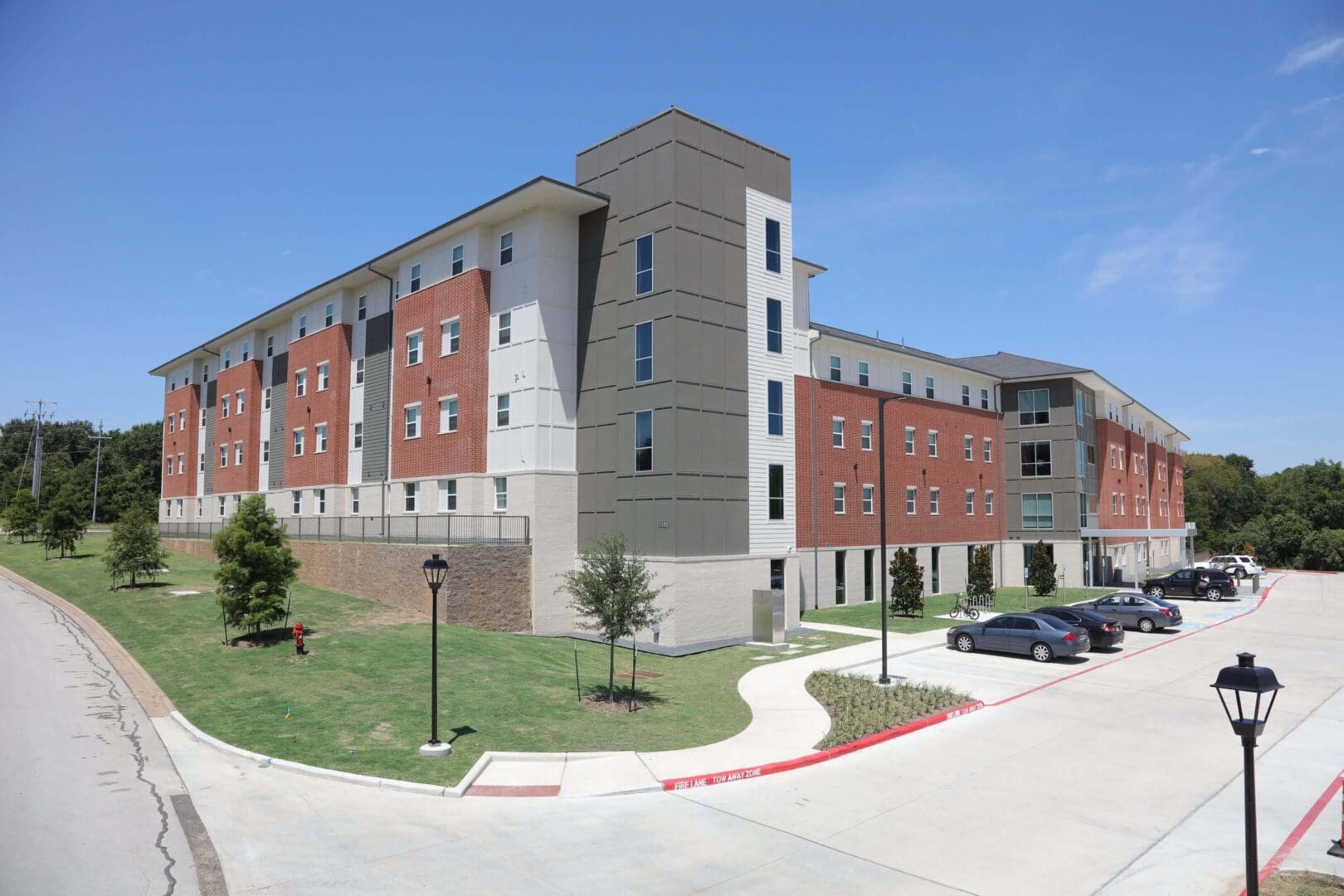 A modern five-story building with brick and beige exterior under a clear blue sky.