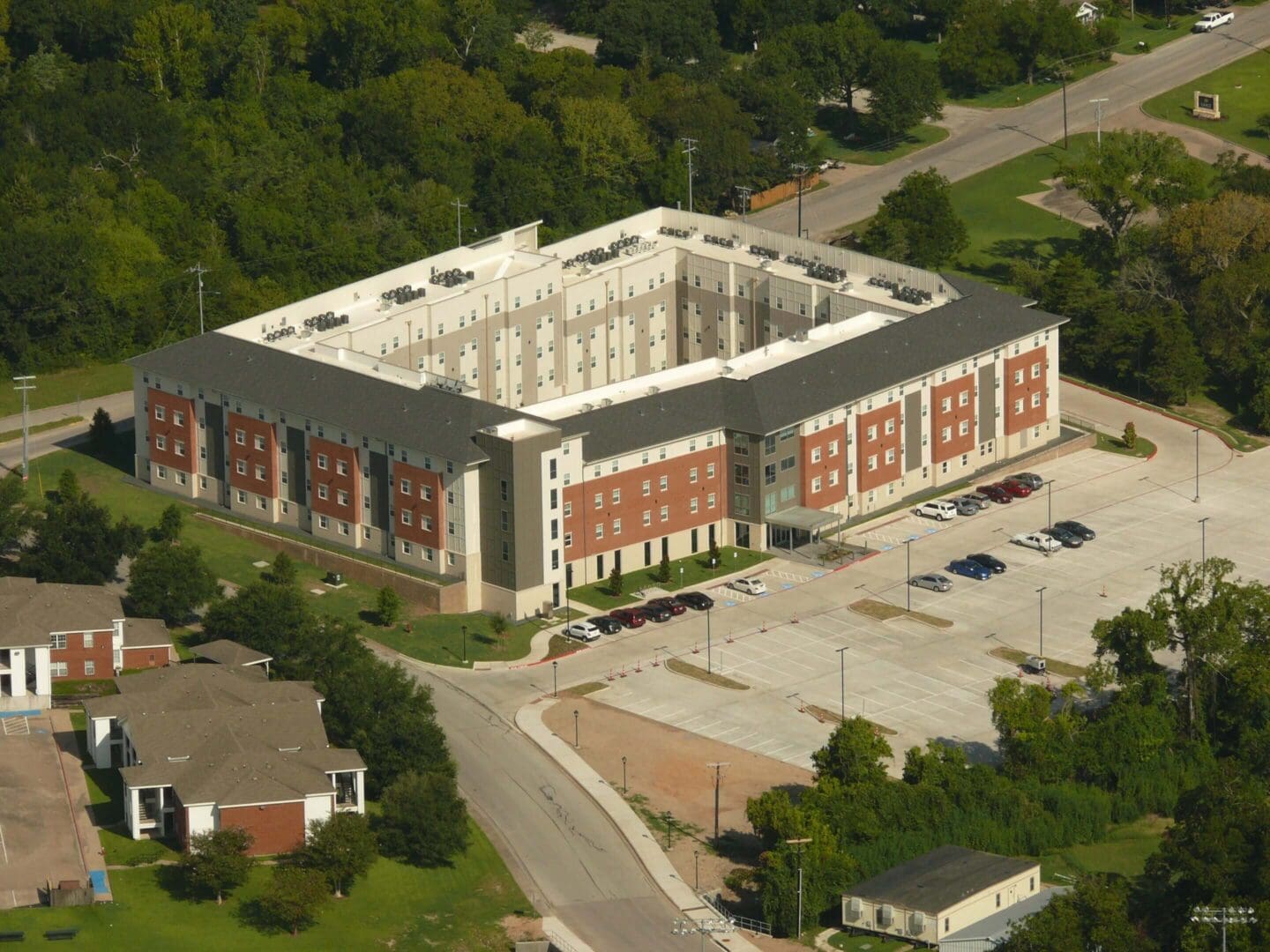 A large institutional brick building with a central courtyard and surrounding parking lot.