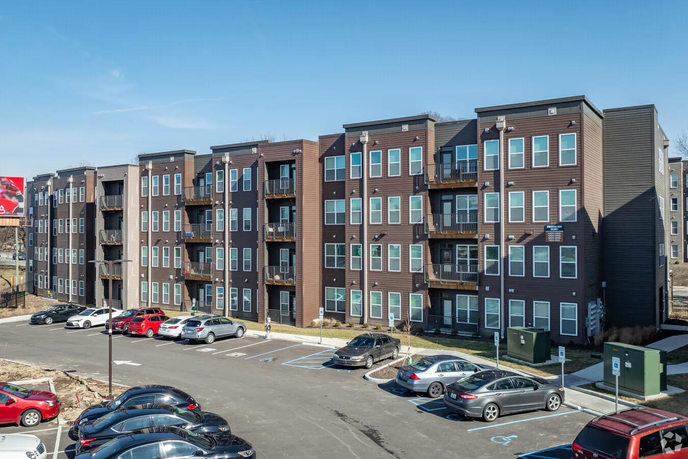 Modern apartment complex with ample parking under a clear blue sky.