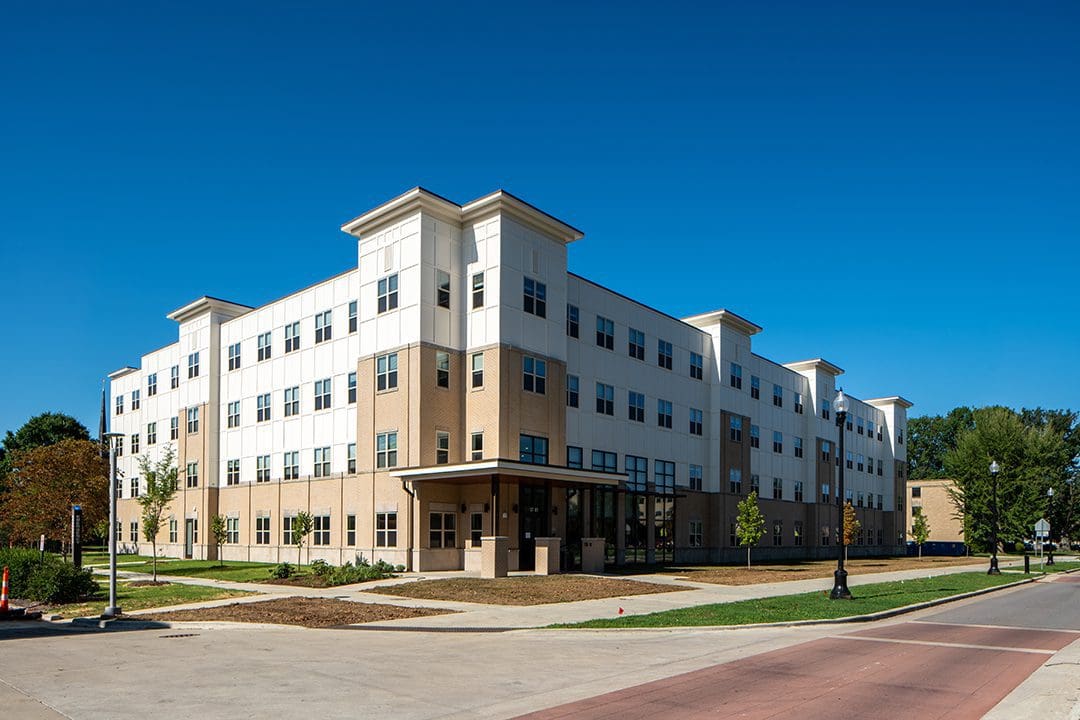 Modern four-story apartment building under a clear blue sky.