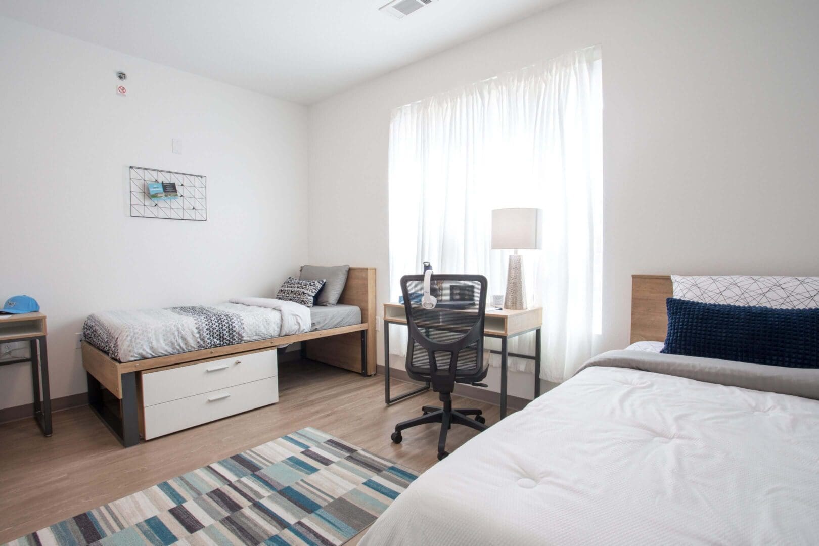 Bright, modern bedroom with two beds and a study area.