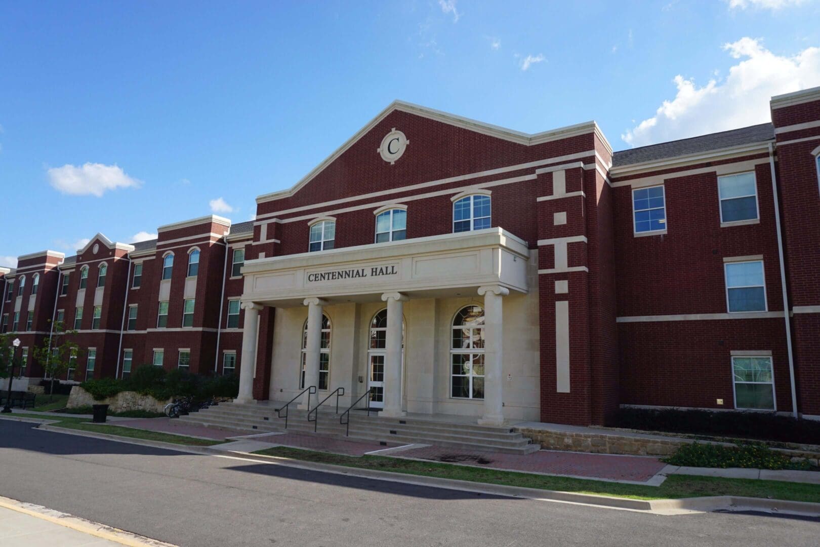 Front view of a classic red brick school building with white columns.