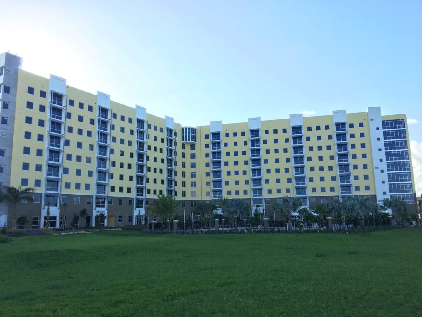 Large yellow and blue apartment complex behind a green lawn.